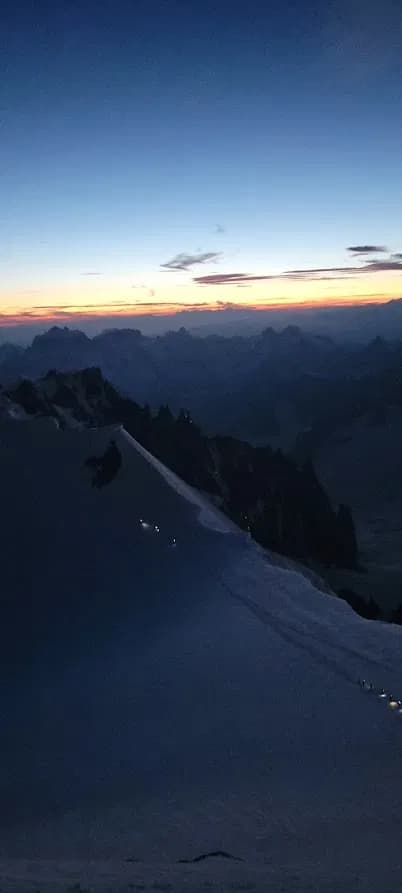 Sonnenaufgang und Bergsteiger mit Stirnlampe am Weg zum Mont Blanc von der Cosmique Hütte